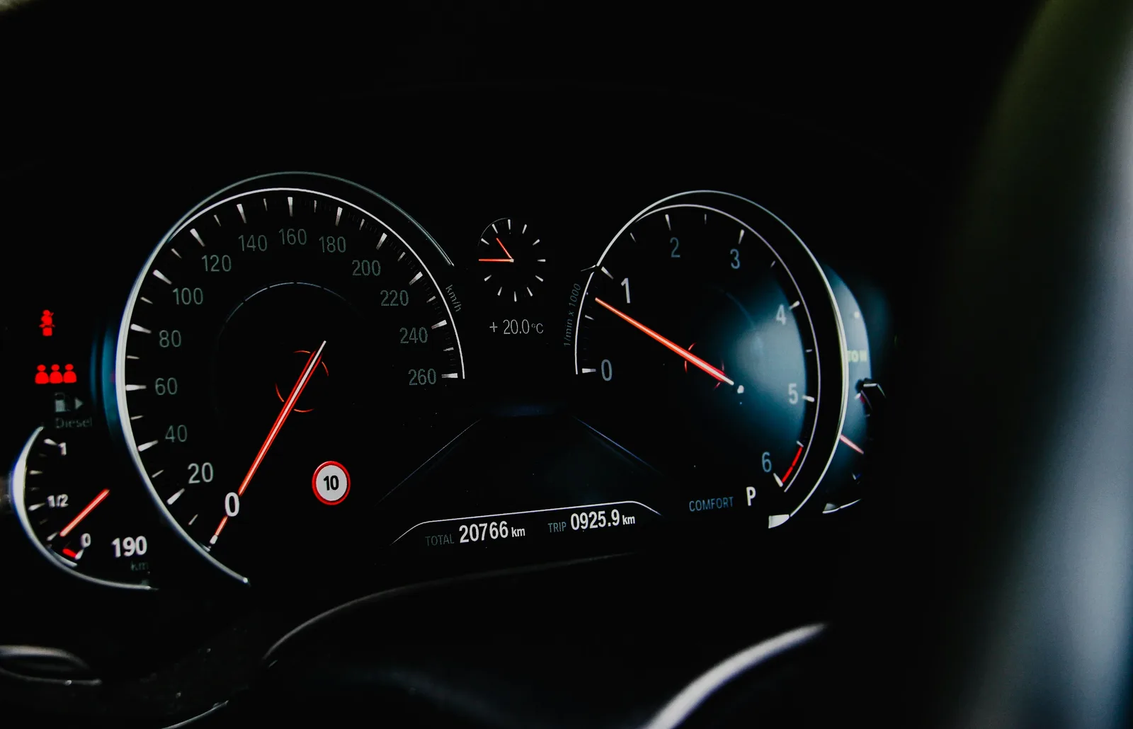 A close-up macro shot of a vehicle gauge cluster showing speedometer and odometer dials in low light