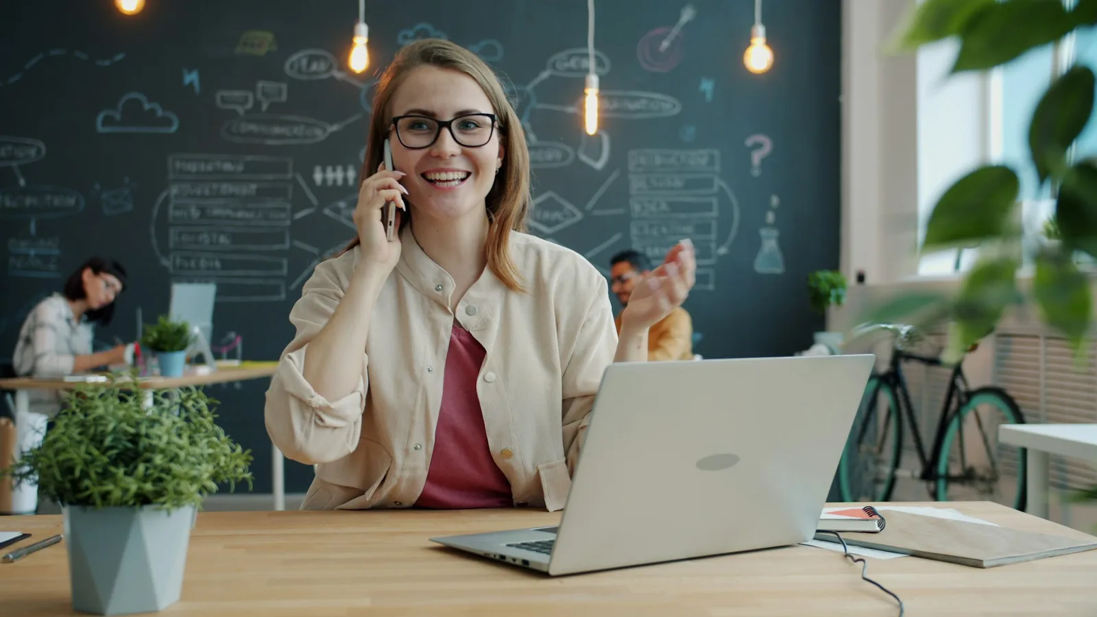 Smiling scheduler in a modern office talking on the phone, illustrating positive coverage confirmation