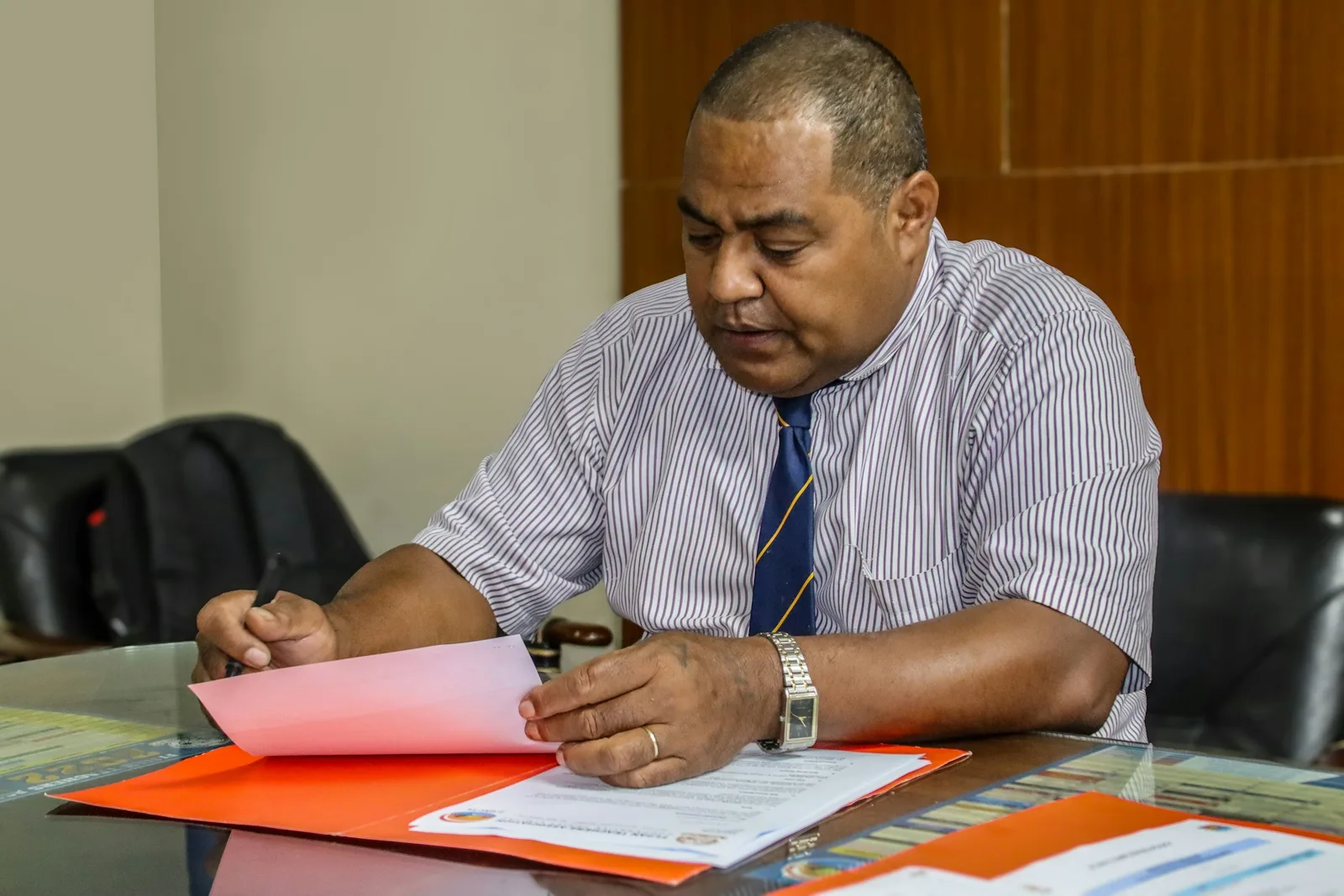 A home care HR manager seated at a table with papers and a laptop reviewing caregiver files