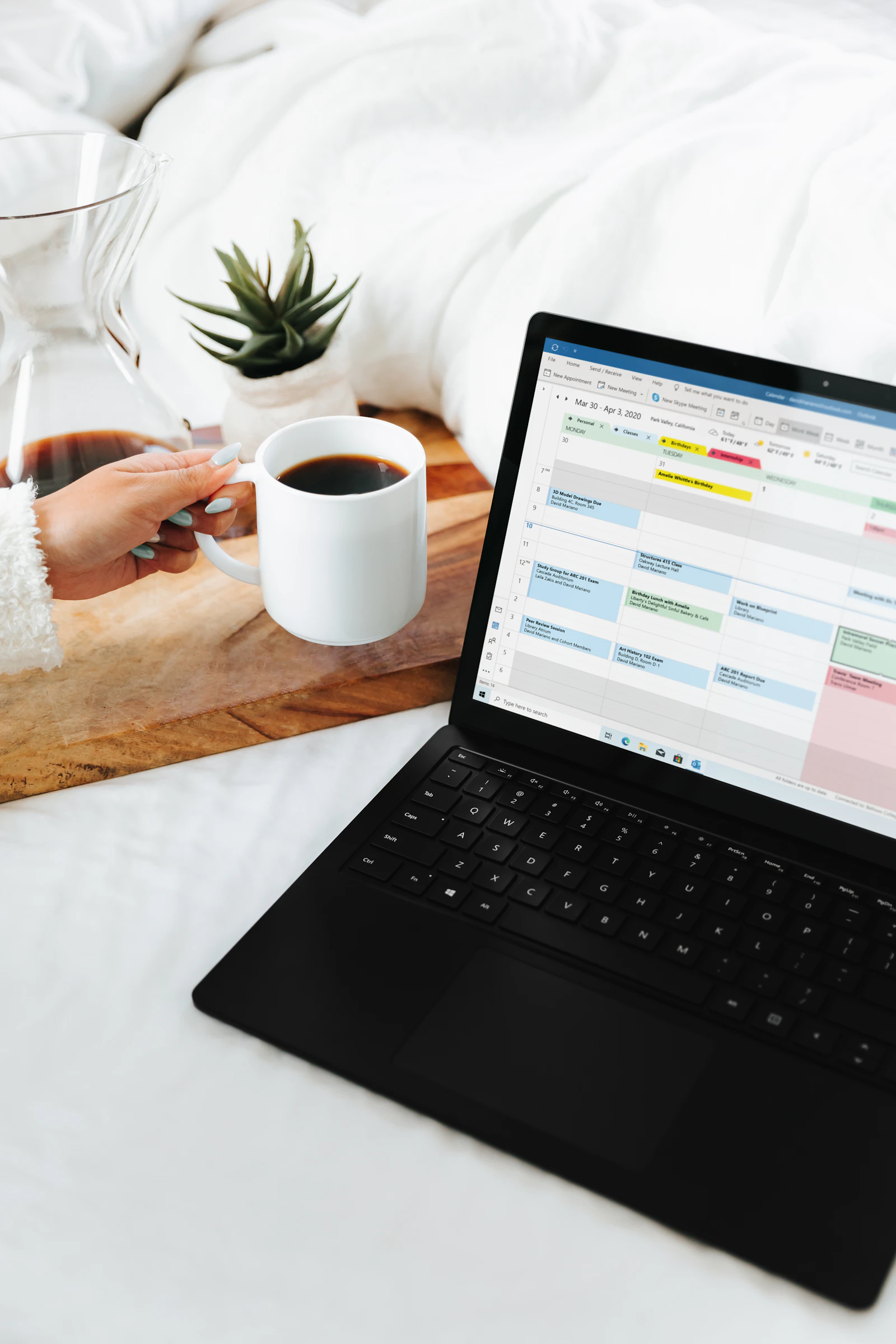 Home care agency owner reviewing a caregiver schedule on a laptop next to a coffee
