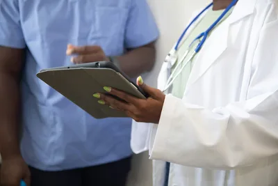 Doctor in white coat showing a patient information on a tablet computer during a clinical visit