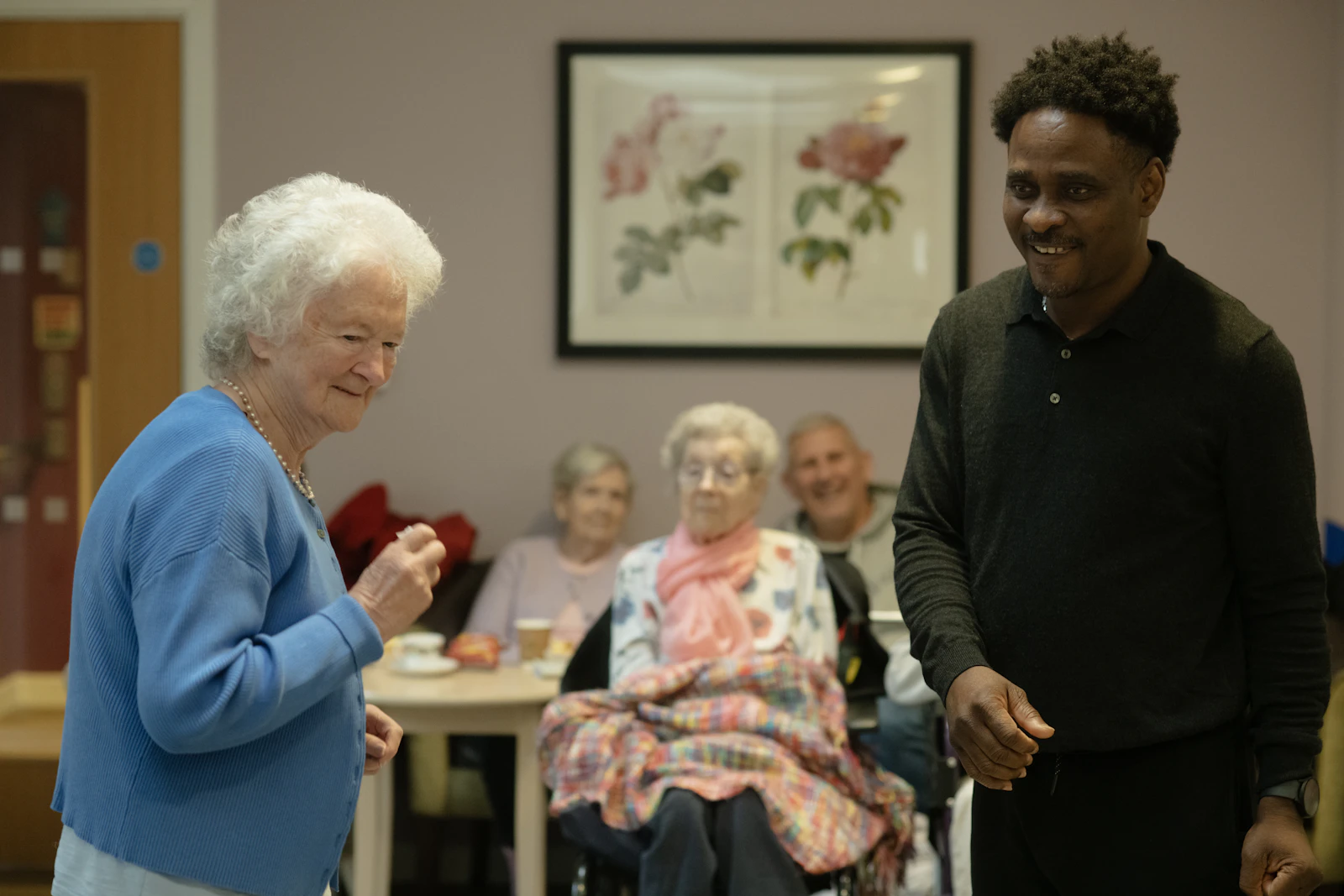 Caregiver with elderly clients in a common-room setting, representing daily care visits