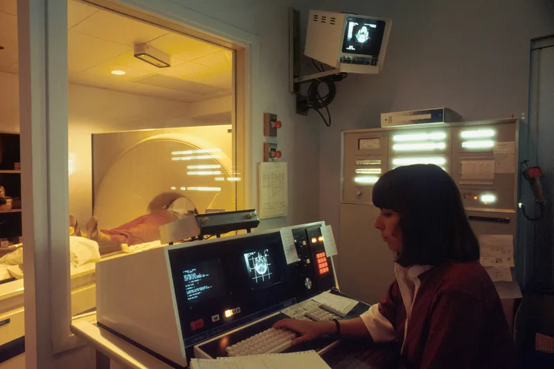 A woman in a professional setting seated in front of an open laptop computer, reviewing information on screen