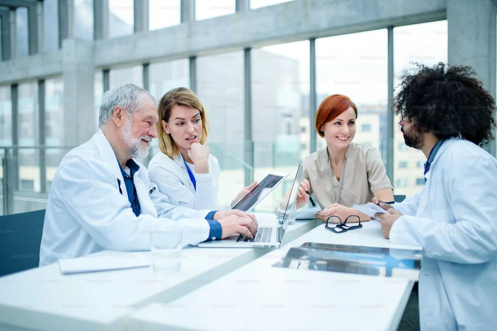 A group of clinicians gathered around a laptop in a conference room reviewing case material