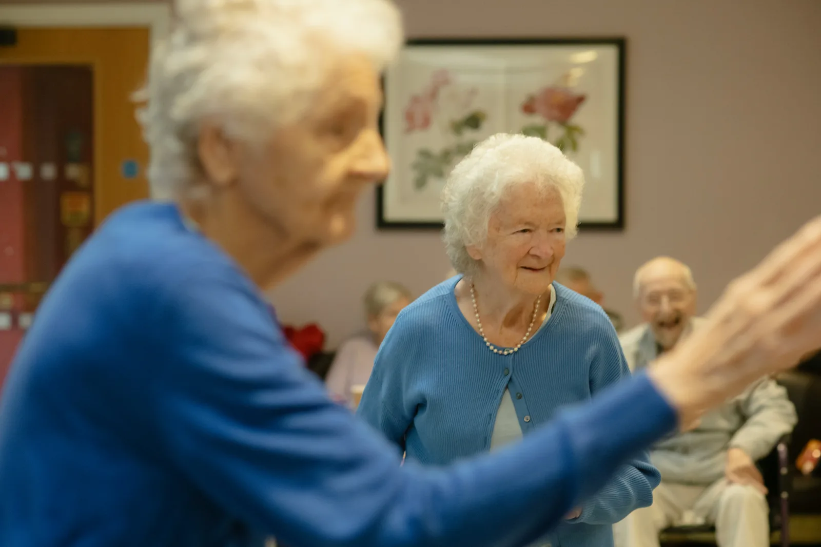 Group of elderly adults participating in a seated group activity together in a bright community room