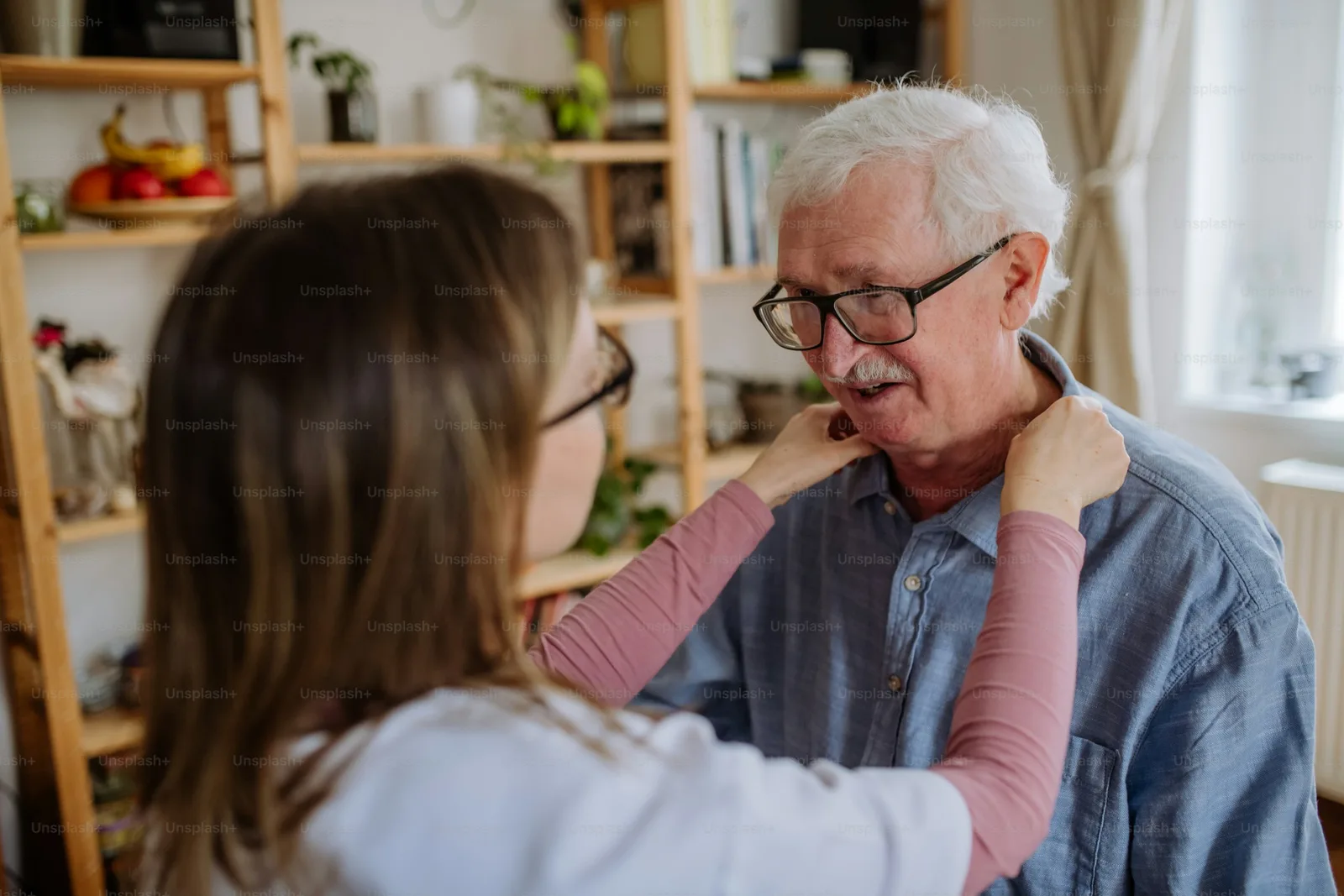 A home care worker assisting a senior man indoors at his home during a visit.