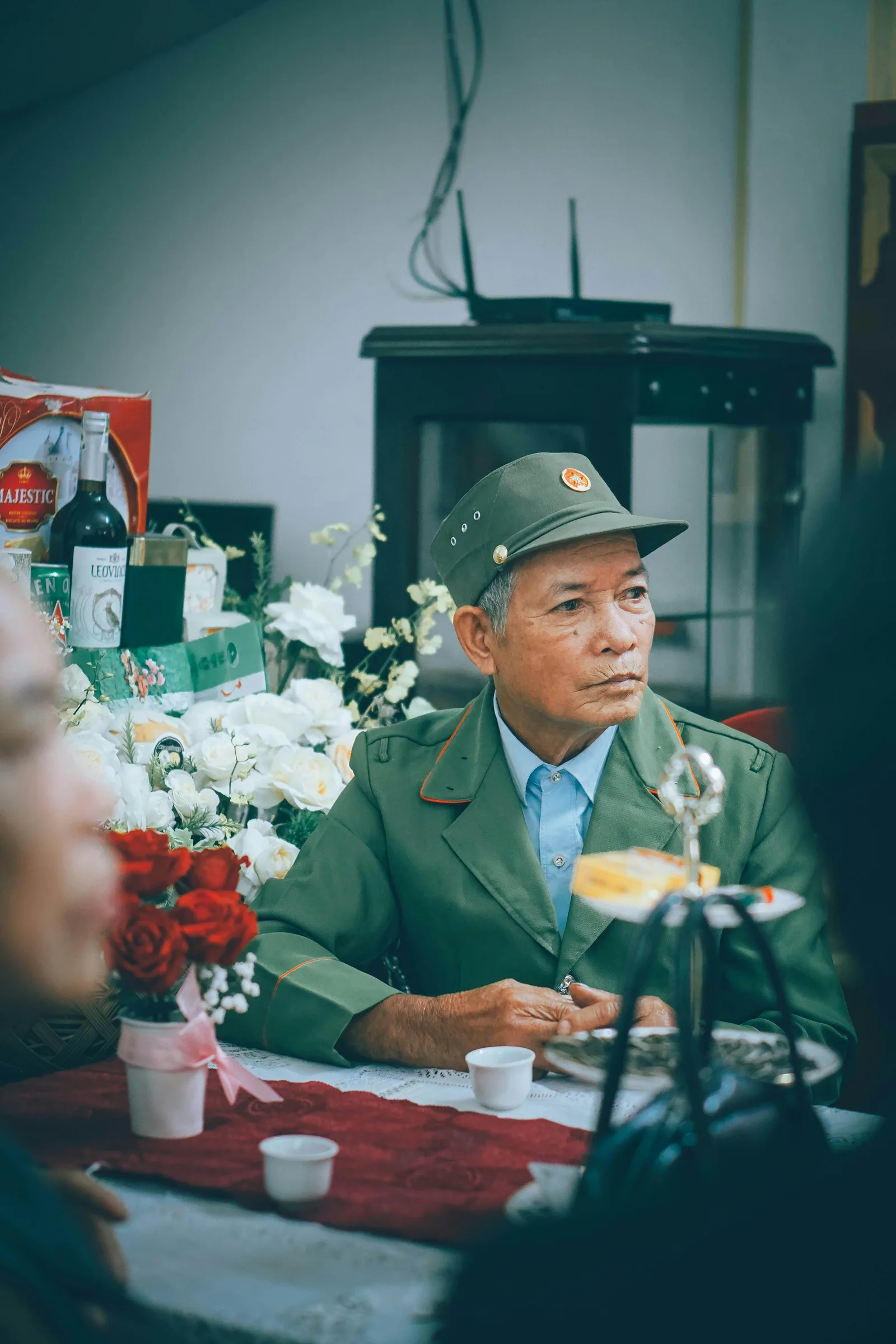 An elderly man in military dress uniform standing at a formal gathering.