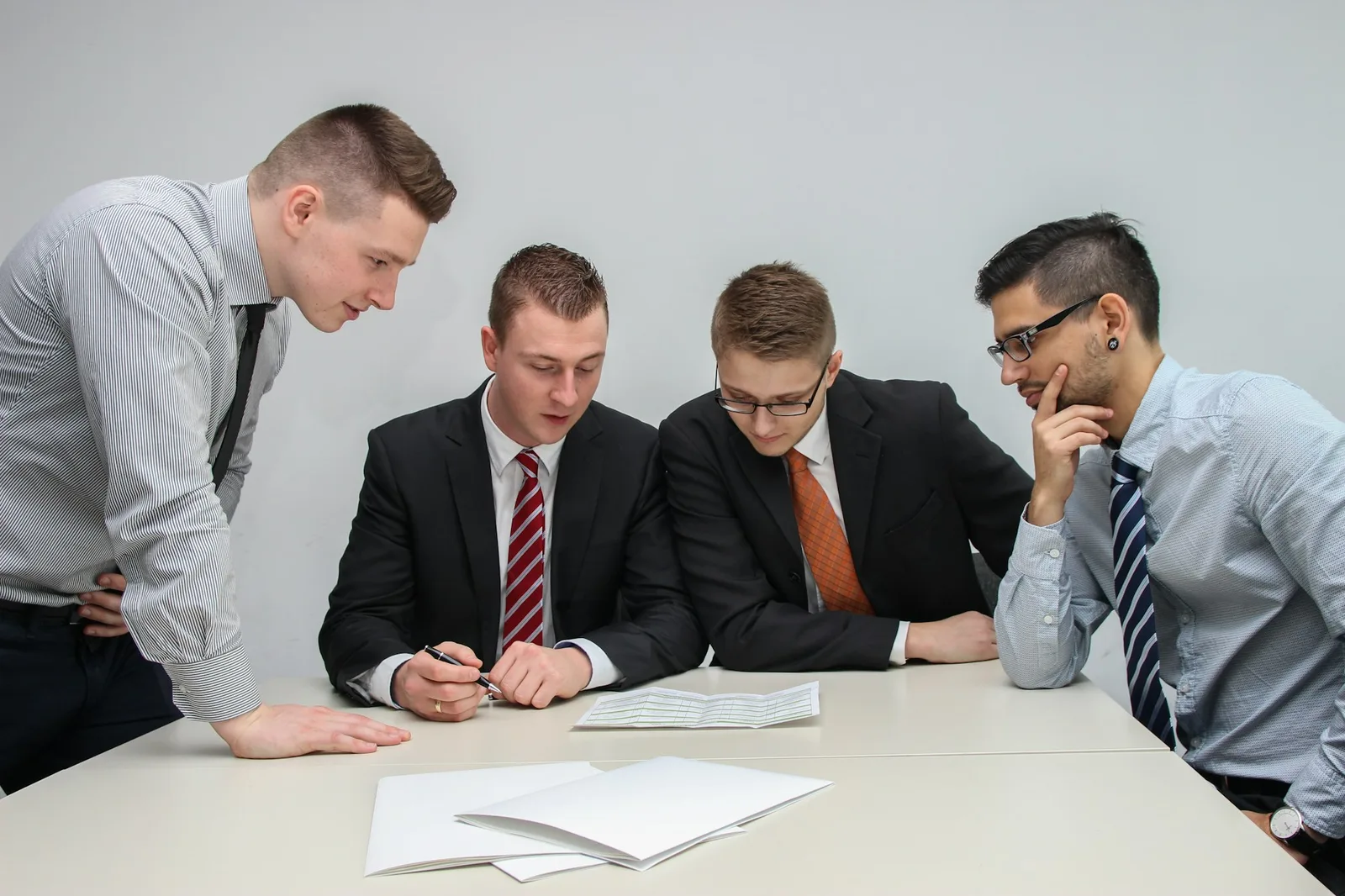 Four people seated around a table reviewing paperwork in a professional meeting