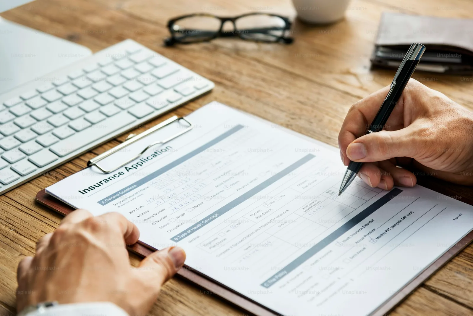 Health and life insurance application paperwork on a desk with a pen