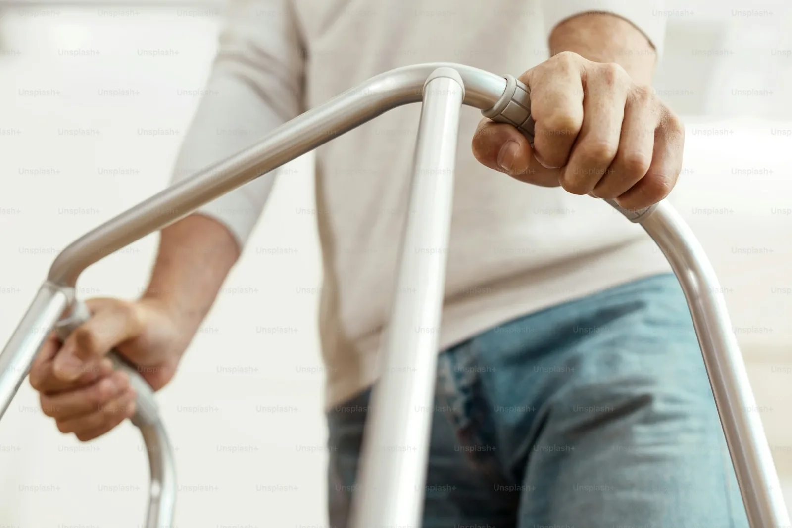 A senior man standing and steadying himself with a four-wheeled walker during mobility practice