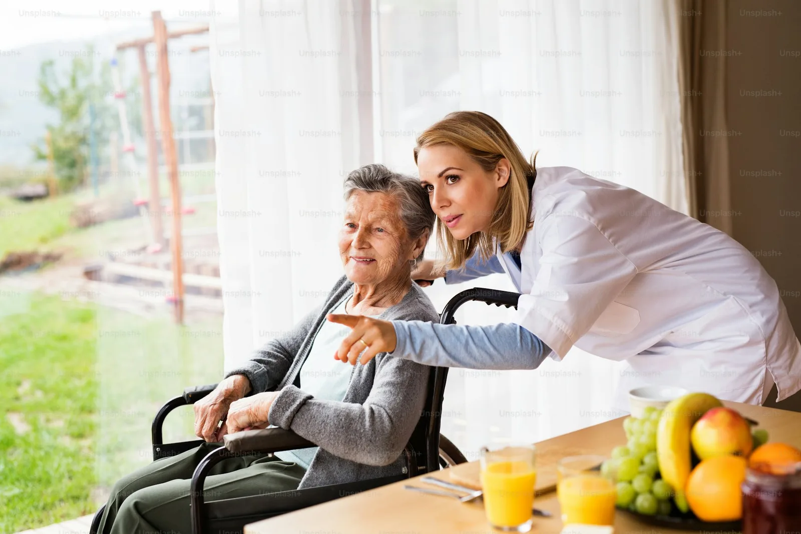 A home care nurse talking with a senior woman seated in a wheelchair during a home visit