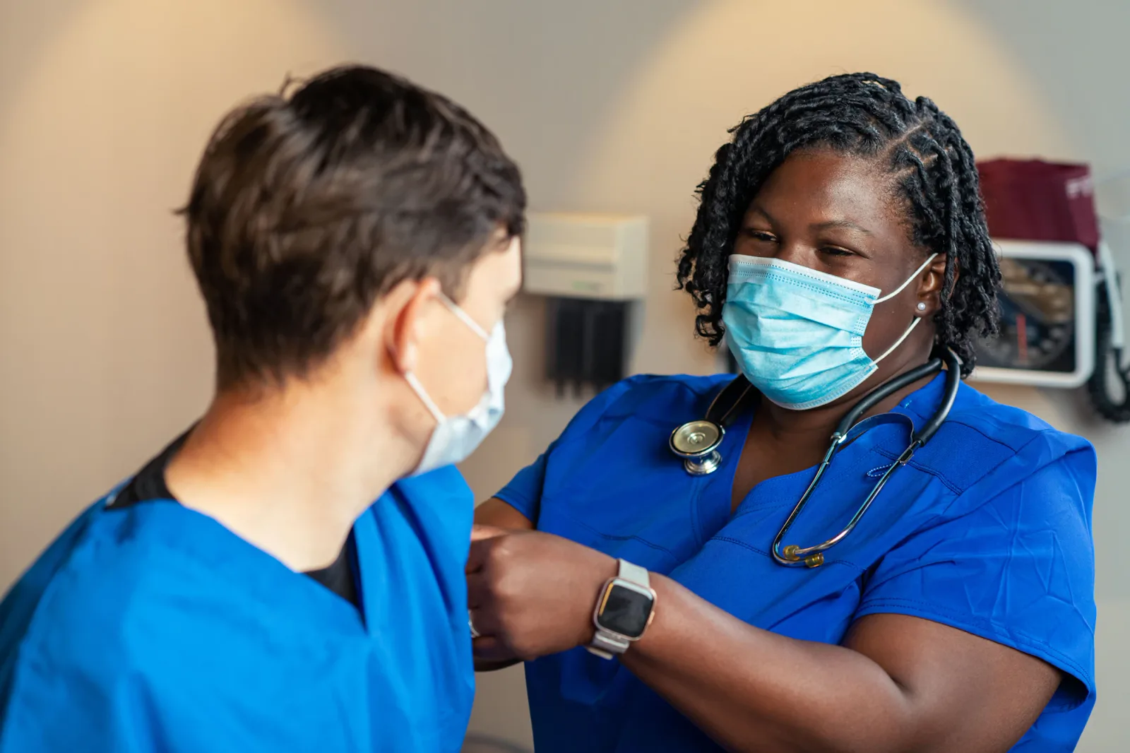 Two home health clinicians in blue scrubs reviewing a patient chart together