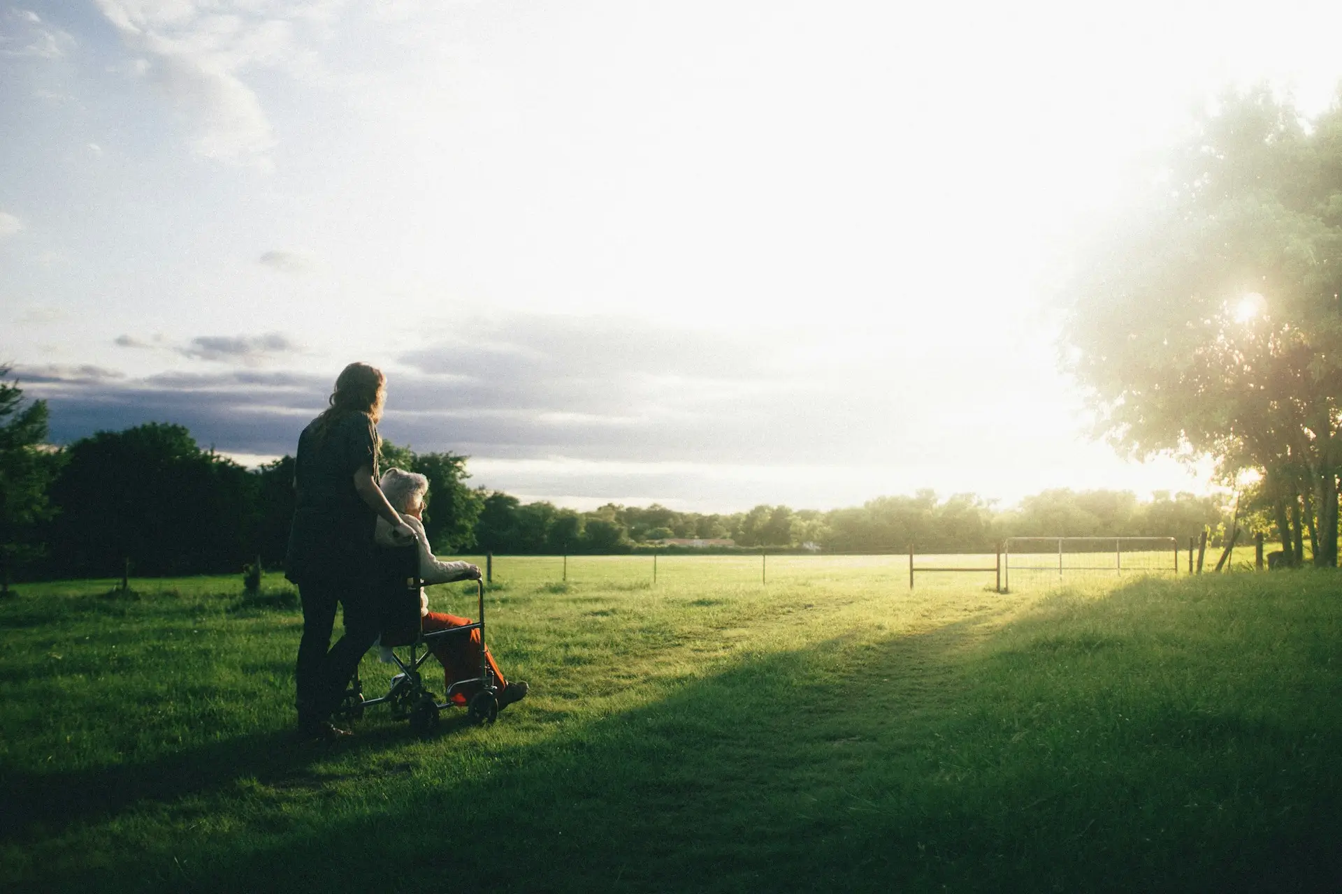 Certified caregiver helping woman in wheelchair during sunset walk